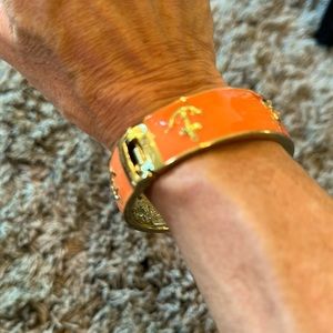 Gold and orange metal bracelet with repeating anchor motif.